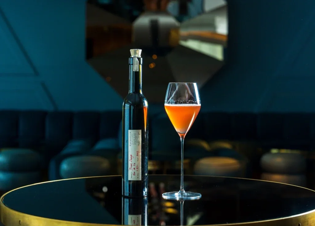 An orange cocktail next to a bottle of Capreolus