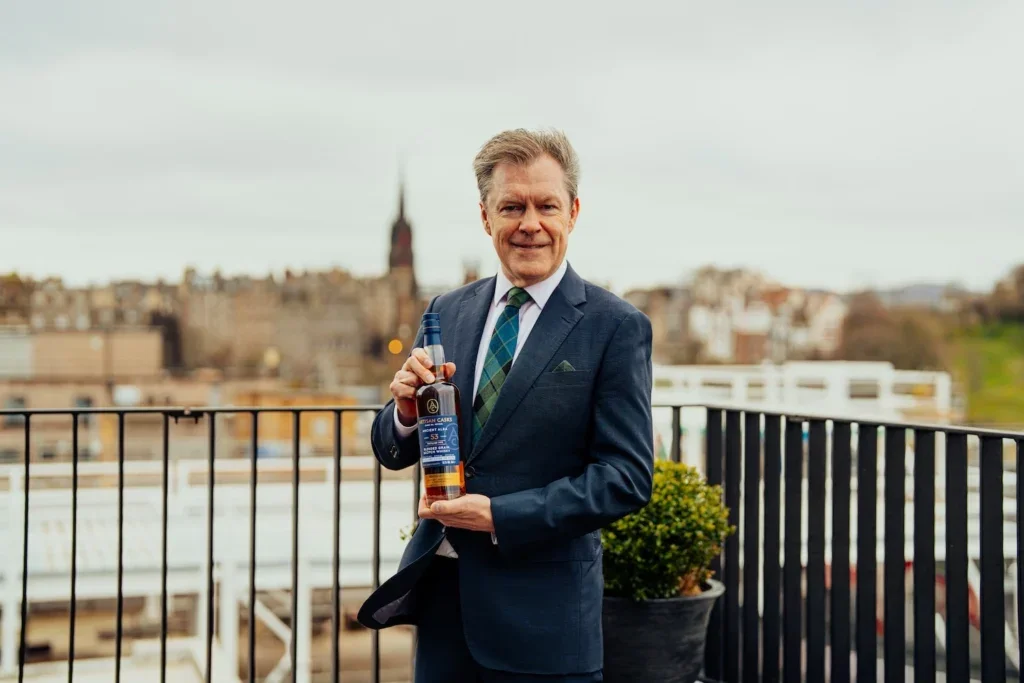 a man holding a bottle of whisky on a balcony